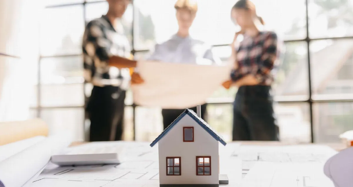 Maquette de maison devant une équipe consultant des plans